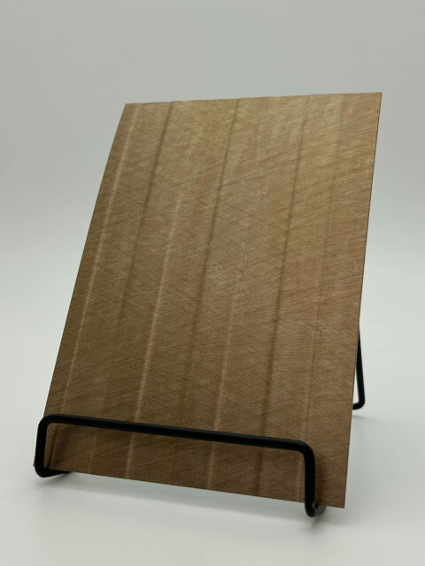 Display stand with a sandy-metallic scratched faux leather panel. The structure features vertical lines that are both recessed and raised.