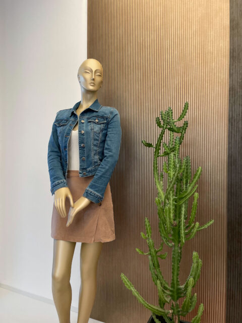 Mannequin and cactus in front of a sandy-metallic design panel made of artificial leather, whose structure is characterized by broad vertical lines.