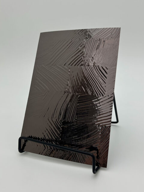 Aufsteller mit einem Designpaneel. Die Struktur ist strukturiert kariert, sowie glänzend spiegelnd und die Farbe ist Anthrazit.