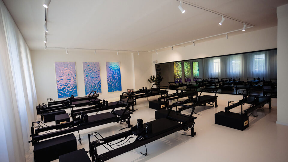 Fitnessstudio modern eingerichtet mit schwarzen Geräten und weißen Wänden mit großen spiegelnde Bildern an der Wand im Weitwinkel aufgenommen