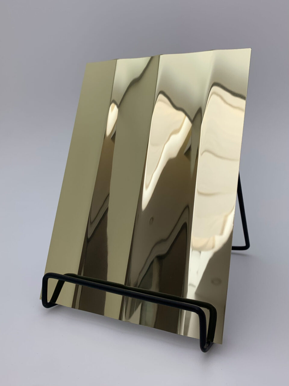 Display stand with a golden, reflective design panel, its structure characterized by broad, vertical lines. The heights and depths of the structure create a particularly deep effect that is truly impressive.