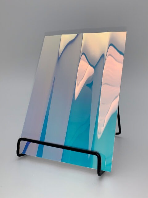 Display stand with a silver, reflective design panel, its structure characterized by broad, vertical lines. The heights and depths of the structure create a particularly deep effect that is truly impressive.