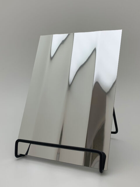 Display stand with a silver, reflective design panel, its structure characterized by broad, vertical lines. The heights and depths of the structure create a particularly deep effect that is truly impressive.