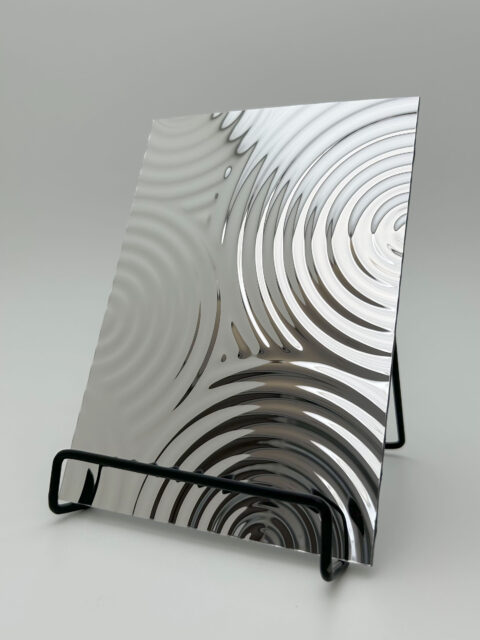 Display stand with a reflective silver design panel, the structure of which shows circles of different sizes that appear one after the other and contain smaller circles within themselves.