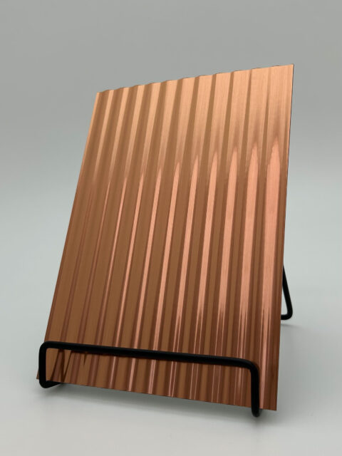 Display stand with a brushed, copper-colored design panel whose structure is characterized by wide vertical lines.