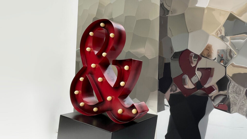 Mirrored design panels on the wall with a hammered finish create an extraordinary reflection of the room. In this case, a red symbol on a black pedestal.