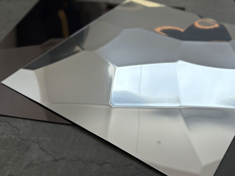 Shown are color variants of the SL FACET wall panel in reflective silver and anthracite. The structure resembles repeatedly folded sheet metal.