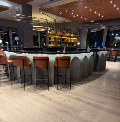 Bar in a modern black style, with brown bar stools with black legs in the foreground