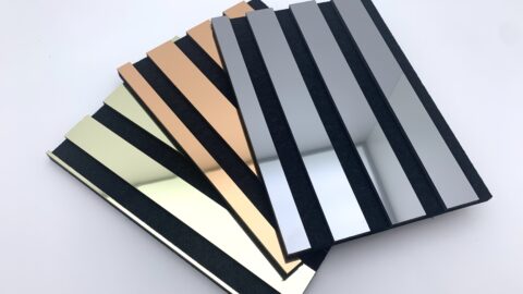 Three reflective acoustic panel samples, fanned out on a white table, reflecting the ceiling.