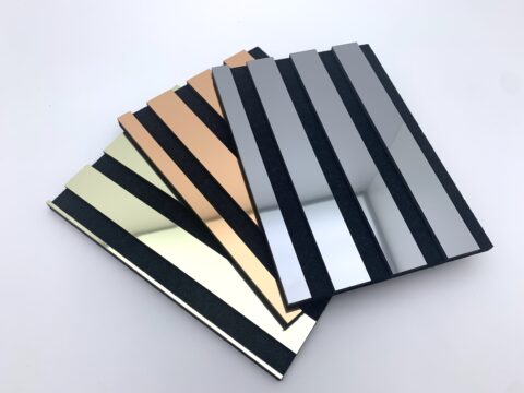 Three reflective acoustic panel samples, fanned out on a white table, reflecting the ceiling.