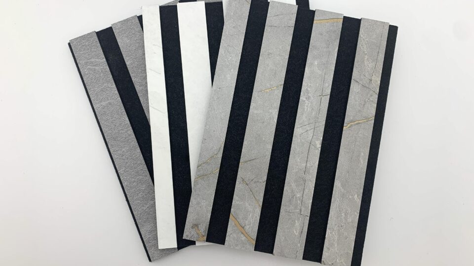 Three acoustic panel samples in stone finish, fanned out on a white table.