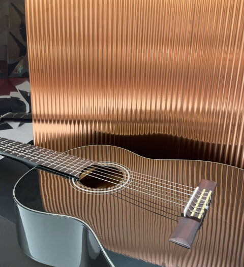 black guitar reflecting a copper-coloured structure